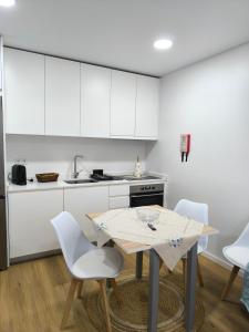 a kitchen with white cabinets and a table and chairs at Alojamento Emílio T1 in Gafanha da Encarnação +7 photos