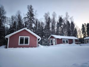 a red house in the snow with trees in the background at Holmens Boende och Event in Luleå