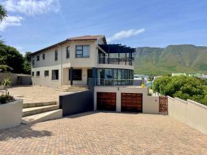 a large white house with a driveway and mountains at Bird's View Guest Accommodation in Hermanus
