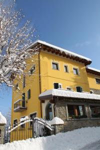 um edifício amarelo com neve em frente em Hotel Gabriella em Fanano