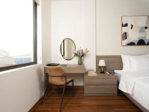 a bedroom with a bed and a desk with a mirror at Dresidence Hotel Ninh Binh in Ninh Binh