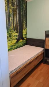 a bed in a room with a painting of a forest at Appartement 7 101 in Goslar