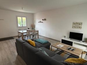 salon z kanapą i stołem w obiekcie Maison Mitoyenne avec cour + parking w mieście Sainte-Savine