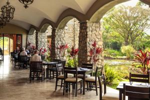 a restaurant with tables and chairs and a pond at Los Mandarinos Boutique Hotel & Spa in Valle de Anton