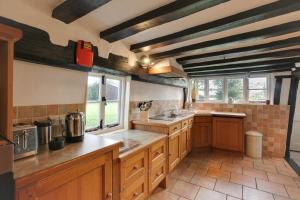eine große Küche mit Holzschränken und Fenstern in der Unterkunft Willow Cottage in Saxtead