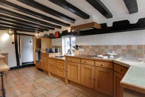 eine große Küche mit Holzschränken und einer Arbeitsplatte in der Unterkunft Willow Cottage in Saxtead + 8 Fotos