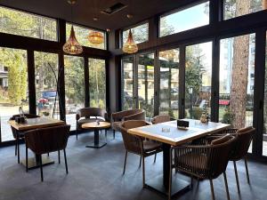 a restaurant with tables and chairs and large windows at Šafran Zlatibor in Zlatibor