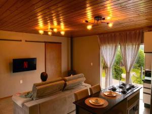 a living room with a couch and a table at Chalé Sunset com Hidro, lareira, piscina, cavalo, trilha, tiro ao alvo in Bento Gonçalves
