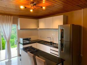 a kitchen with a stainless steel refrigerator and a counter at Chalé Sunset com Hidro, lareira, piscina, cavalo, trilha, tiro ao alvo in Bento Gonçalves