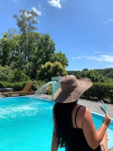 a woman wearing a hat sitting next to a swimming pool at Chalé Sunset com Hidro, lareira, piscina, cavalo, trilha, tiro ao alvo in Bento Gonçalves