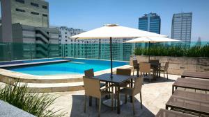 a table with chairs and an umbrella next to a pool at Studio Orion in Rio de Janeiro