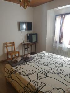 a bedroom with a bed and a chair and a television at Locanda In Montagna Da Emili&Gabriel in Lizzano in Belvedere