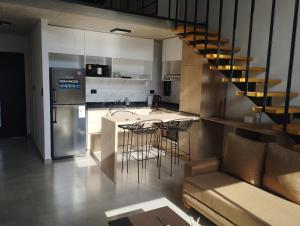 a kitchen with a bar with stools and a refrigerator at Loft CienHojas in San Luis
