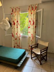 a bedroom with a bed and a chair and a window at Summerhouse Marianna in Ixia