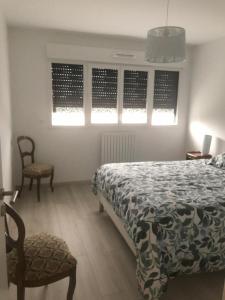 a bedroom with a bed and a chair and windows at Henea in Saint-Paul-lès-Dax