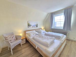 a bedroom with a bed and a chair and a window at Ferienhaus Teddis Haus in Norden