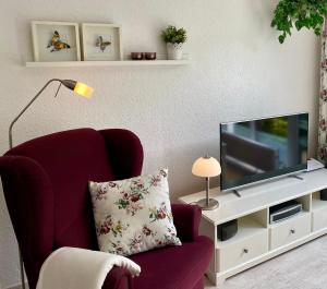 a living room with a red chair and a tv at Lodge 2 Bad Harzburg in Bad Harzburg