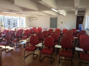 a room with red chairs and desks in a classroom at Colle Tourist Hotel Standard Sem Elevador in Criciúma