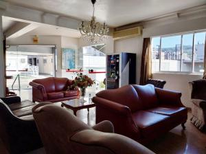 a living room with leather furniture and a chandelier at Colle Tourist Hotel Standard Sem Elevador in Criciúma