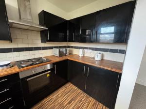 una cucina con mobili neri e un forno a piano cottura di Double-Bedroom in the Heart of Salford Manchester GCSW6 Perfect for Short Stays a Manchester Altre 3 foto