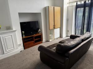 un soggiorno con divano in pelle e TV a schermo piatto di Double-Bedroom in the Heart of Salford Manchester GCSW6 Perfect for Short Stays a Manchester