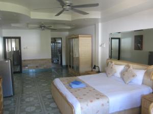 a bedroom with a large bed with a ceiling fan at Borussia Park Guesthouse & Restaurant in Pattaya North