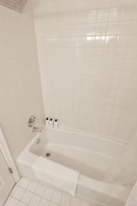 een wit bad in een wit betegelde badkamer bij Capitol Hill & Penn - Steps from Eastern Market in Washington +9 foto's