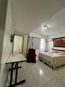 a bedroom with a bed and a table and a chair at Colle Tourist Hotel Standard Sem Elevador in Criciúma