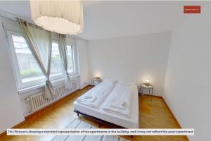 a white bedroom with a bed and a chandelier at Cozy & Basic 4-Bedroom Stay Near Zurich in Zollikon