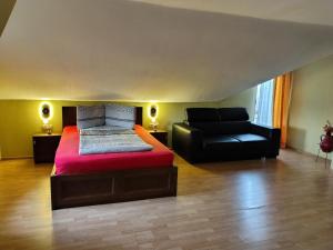 a bedroom with a bed and a black couch at VIS PENSION in Viile Satu Mare