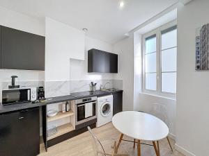 een witte keuken met een tafel en een wit fornuis bovenste oven bij My Home Saint Jérome 2 in Lyon