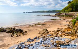 a beach with rocks on the sand and the water at 4 The Strand in Saundersfoot