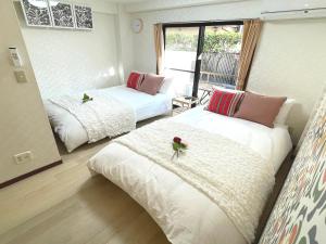 a room with two beds with flowers on them at #3 新宿まで2分! 清潔で安全な部屋! WiFi無料! in Tokyo