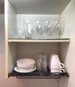 a shelf with wine glasses and plates and a pitcher at #3 新宿まで2分! 清潔で安全な部屋! WiFi無料! in Tokyo