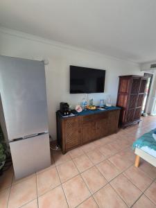 a living room with a refrigerator and a flat screen tv at Studio Ti Gwama Village Vacances in Sainte-Anne