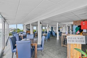 a restaurant with blue chairs and tables and a sign at Edge of the Avalon Inn in Trepassey