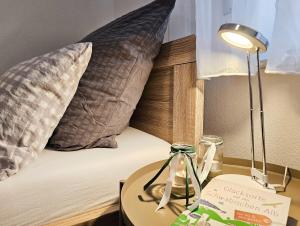 a lamp on a table next to a bed with pillows at Ferienwohnung Reimann mit kostenloser AlbCard in Blaubeuren +11 photos