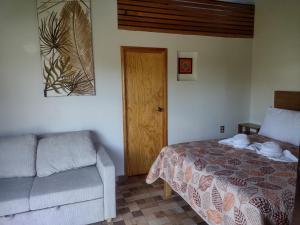 una camera con un letto e un divano accanto a una porta di Aldea Xochi cabañas a Chiconcuac