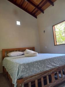 a bedroom with a bed with blue sheets and a window at Aldeia Raizama - Casa Copa in Alto Paraíso de Goiás