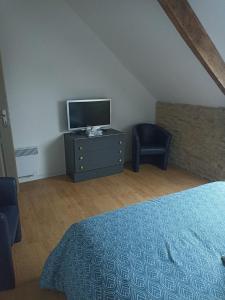 Un dormitorio con una cama, un televisor y una silla. en Maison de pierre entre golfe et Océan, en Sarzeau