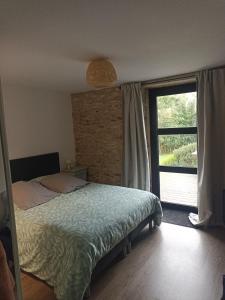 Un dormitorio con una cama y una ventana grande. en Maison de pierre entre golfe et Océan, en Sarzeau