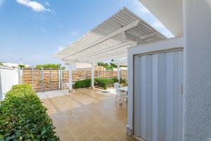 a patio with a white pergola and a table at Punta Prosciutto Bed in Torre Lapillo