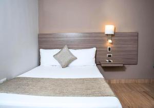 a bedroom with a white bed with a wooden headboard at Betania Hotel in Santa Marta +3 photos