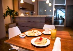 a wooden table with two plates of food and orange juice at Betania Hotel in Santa Marta