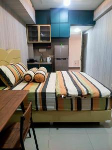 a room with two beds and a table and a kitchen at Apartemen Anderson Benson Tanglin Orchard in Surabaya