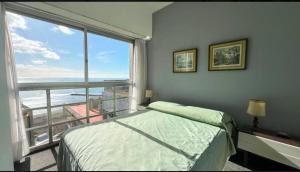 a bedroom with a bed and a large window at Departamento frente al mar tres dormitorios in Mar del Plata
