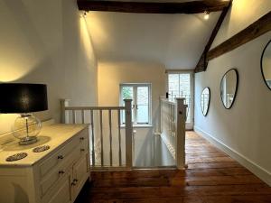 a room with a staircase with a dresser and mirrors at The Cottage, Upper Linney, Ludlow in Ludlow