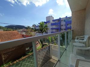 ein Balkon mit Stühlen und Blick auf ein Gebäude in der Unterkunft Pousada raios de sol indaia in Bertioga