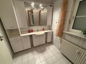 a white bathroom with a sink and a mirror at Charmante Ferienwohnung in Garbsen Stilvoll Geräumig in Garbsen +7 photos