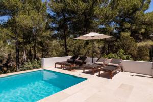ein Swimmingpool mit zwei Stühlen und einem Sonnenschirm in der Unterkunft Villa Can Secorrat in Can Furnet
